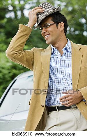 Stock Image - Hispanic man putting on hat. Fotosearch
