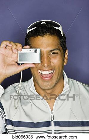 Stock Photography - Hispanic man taking photograph with camera. Fotosearch
