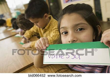 Stock Image - Hispanic school girl displaying name card. Fotosearch
