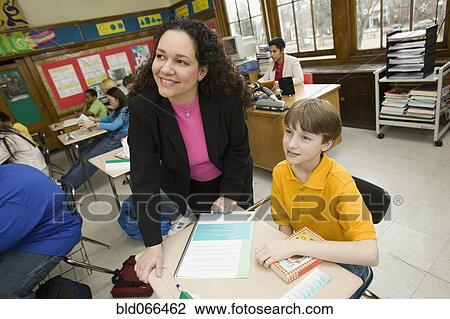Stock Image - Hispanic school teacher helping student. Fotosearch