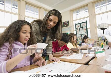 Stock Photo - Hispanic school teacher helping students. Fotosearch