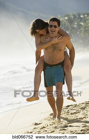 Stock Image - Man giving girlfriend piggyback ride. Fotosearch