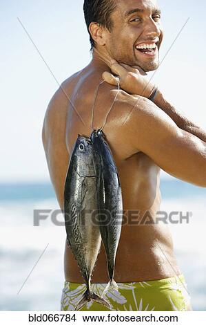 Man standing in ocean carrying fish View Large Photo Image Picture - Man standing in ocean carrying fish. Fotosearch