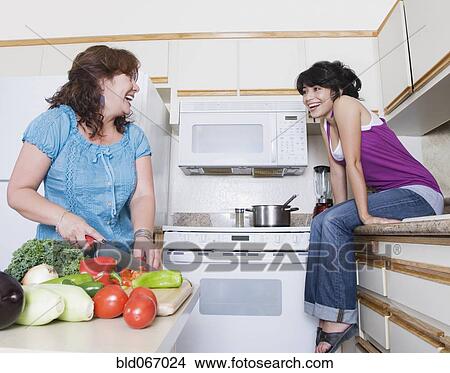 Picture - Mother preparing meal and talking to daughter. Fotosearch