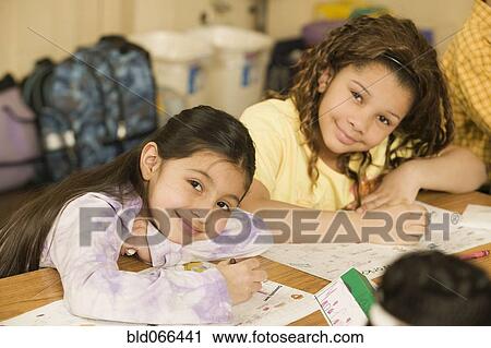 Stock Image - School girls writing at desks. Fotosearch