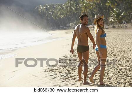 Stock Image - Smiling couple walking on beach. Fotosearch