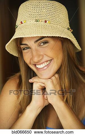Stock Image - Smiling woman wearing straw hat. Fotosearch