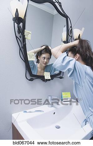 Picture - Woman getting ready in front of mirror. Fotosearch