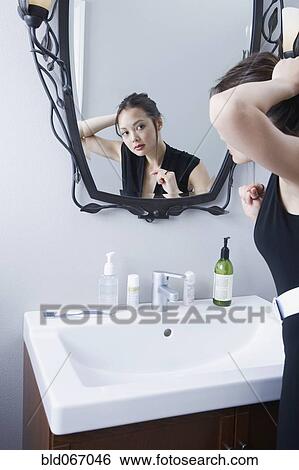 Stock Photograph - Woman getting ready in front of mirror. Fotosearch