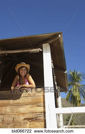 Stock Image - Woman in lifeguard tower at beach. Fotosearch
