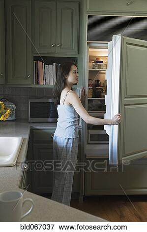 Stock Photo - Woman opening refrigerator door. Fotosearch