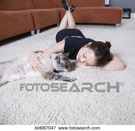 Stock Photo - Woman petting cat on floor. Fotosearch