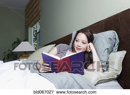 Stock Photo - Woman reading book in bed. Fotosearch