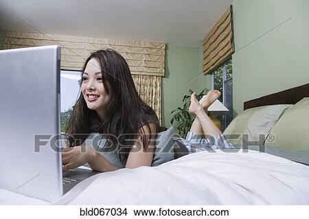 Woman using laptop in bed View Large Photo Image Picture - Woman using laptop in bed. Fotosearch
