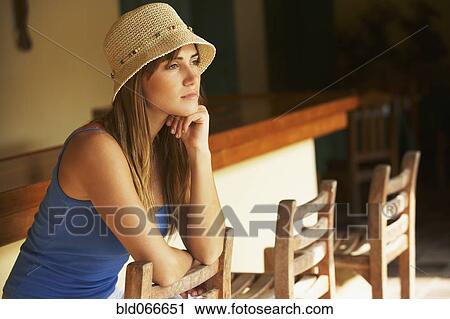 Stock Image - Woman wearing straw hat in bar. Fotosearch