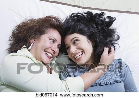 Picture - Young woman and mother laughing on bed. Fotosearch