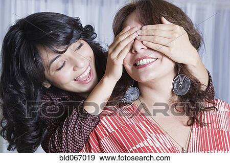 Stock Photo - Young woman covering mother’s eyes. Fotosearch