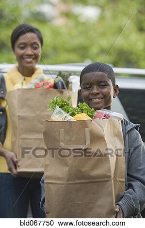 African boy helping mother unload groceries View Large Photo Image Stock Image - African boy helping mother unload groceries. Fotosearch