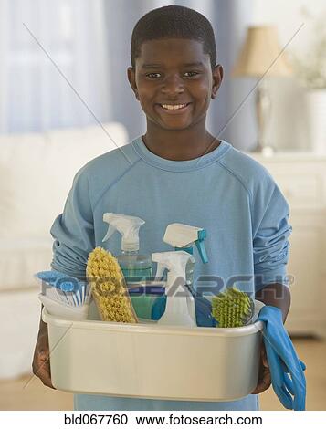 Stock Image - African boy holding bucket of cleaning supplies. Fotosearch