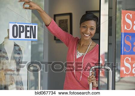 African business owner hanging open sign on shop door View Large Photo Image Picture - African business owner hanging open sign on shop door. Fotosearch