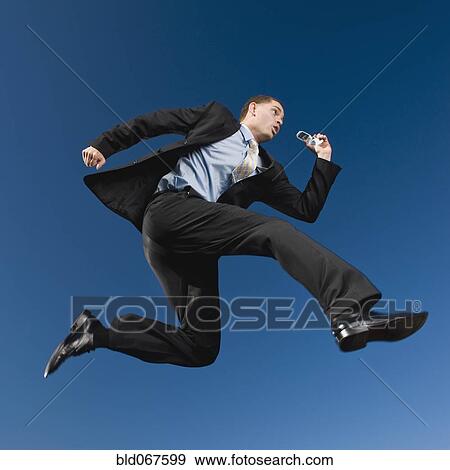 Stock Photo - African businessman in mid-air holding cell phone. Fotosearch