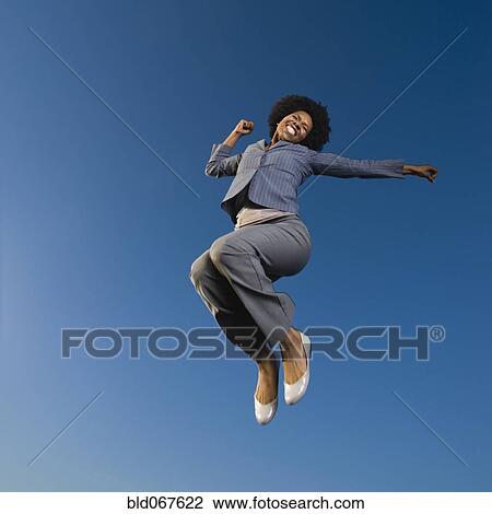Stock Image - African businesswoman jumping in mid-air. Fotosearch