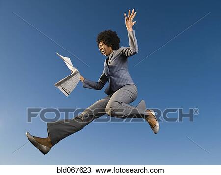 Stock Image - African businesswoman reading newspaper in mid-air. Fotosearch