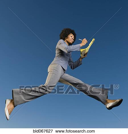 Stock Photo - African businesswoman writing on legal pad in mid-air. Fotosearch