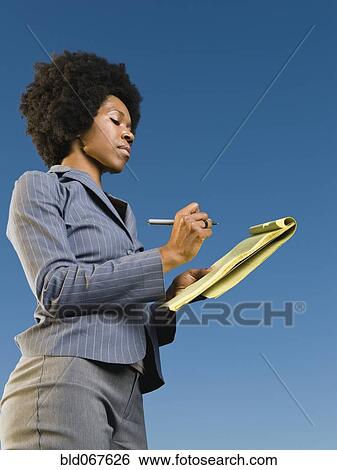 Stock Photograph - African businesswoman writing on legal pad. Fotosearch