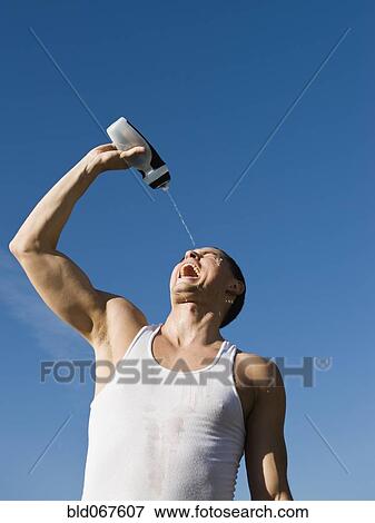 Stock Photo - African man squirting water on his face. Fotosearch