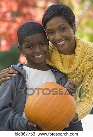 Stock Image - African mother and son holding pumpkin. Fotosearch