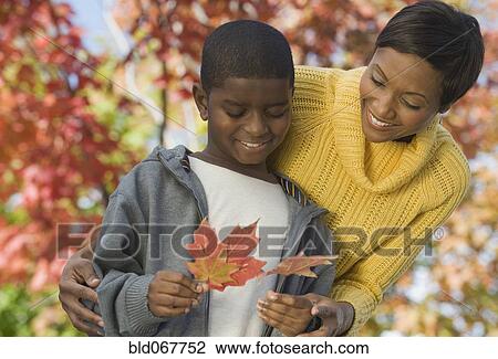 African mother and son looking at autumn leaves View Large Photo Image Stock Image - African mother and son looking at autumn leaves. Fotosearch