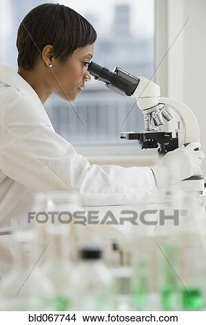 Picture - African scientist peering into microscope. Fotosearch
