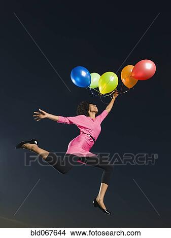 African woman holding bunch of balloons in mid-air View Large Photo Image Picture - African woman holding bunch of balloons in mid-air. Fotosearch