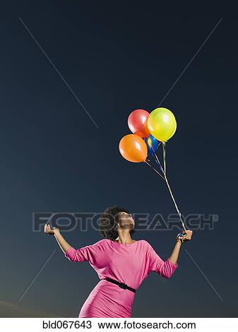 Stock Image - African woman holding bunch of balloons. Fotosearch