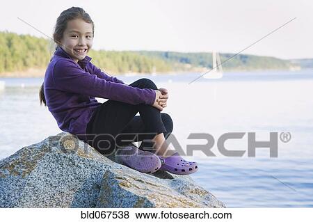 Asian girl sitting on rocky shore View Large Photo Image Stock Photo - Asian girl sitting on rocky shore. Fotosearch