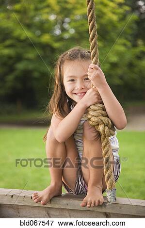 Stock Photo - Asian girl swinging on rope swing. Fotosearch
