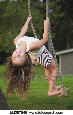 Stock Photograph - Asian girl swinging on rope swing. Fotosearch