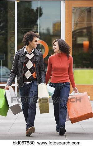 Stock Image - Couple carrying shopping bags. Fotosearch