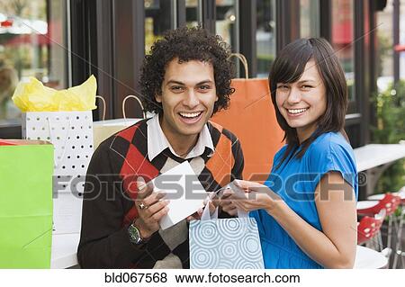Stock Photo - Couple in cafe with shopping bags. Fotosearch