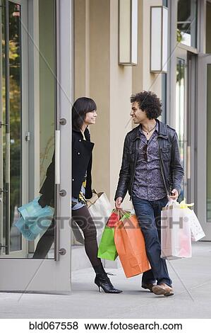 Stock Photo - Couple leaving store with shopping bags. Fotosearch