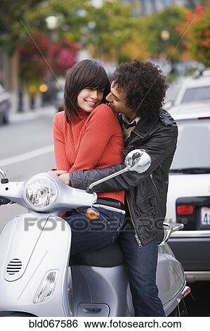 Stock Photograph - Couple sitting on scooter. Fotosearch