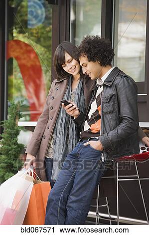 Stock Image - Couple text messaging on cell phone. Fotosearch