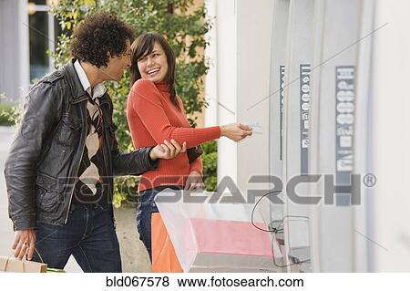 Couple with shopping bags at ATM View Large Photo Image Stock Photo - Couple with shopping bags at ATM. Fotosearch