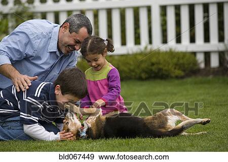 Stock Photo - Family playing with dog in backyard. Fotosearch