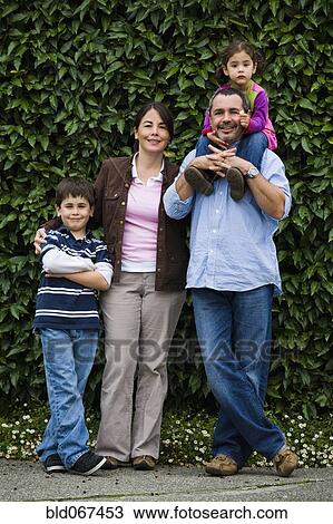 Stock Image - Family posing near hedge. Fotosearch