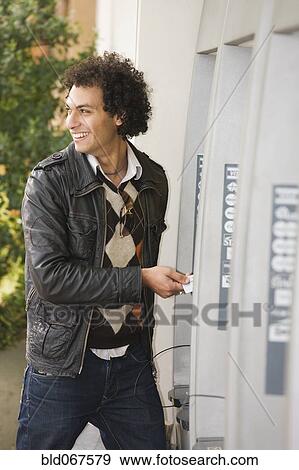 Stock Photo - Middle Eastern man at ATM. Fotosearch
