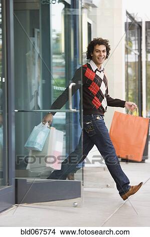 Picture - Middle Eastern man leaving store with shopping bags. Fotosearch