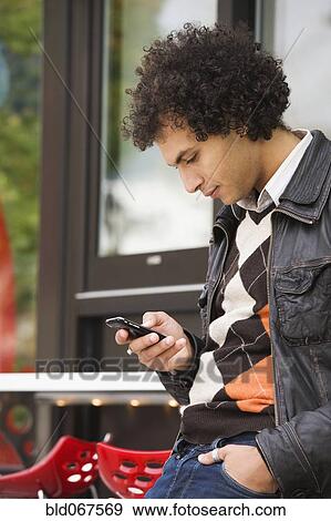 Stock Photo - Middle Eastern man text messaging on cell phone. Fotosearch