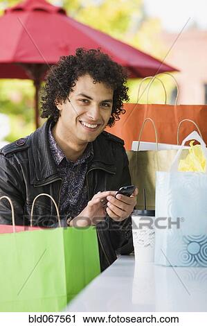 Middle Eastern man with shopping bags text messaging on cell phone View Large Photo Image Stock Image - Middle Eastern man with shopping bags text messaging on cell phone. Fotosearch
